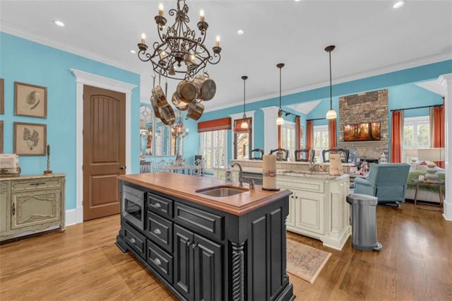 kitchen featuring a center island with sink, decorative light fixtures, sink, and a wealth of natural light