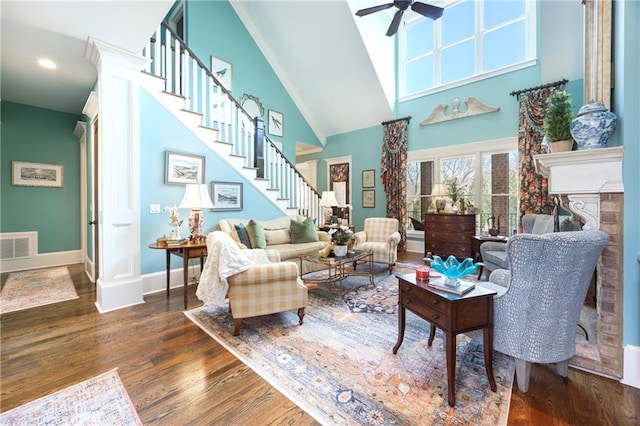 living area featuring wood finished floors, baseboards, a ceiling fan, a tile fireplace, and stairs