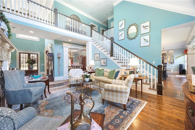 living area featuring wood finished floors, decorative columns, ornamental molding, stairs, and a notable chandelier