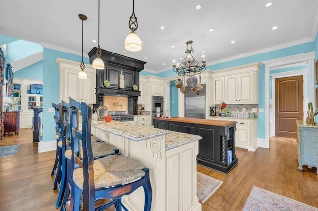 kitchen with appliances with stainless steel finishes, backsplash, pendant lighting, a center island, and butcher block countertops