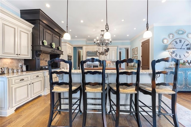 kitchen with light wood finished floors, a kitchen bar, and light stone countertops