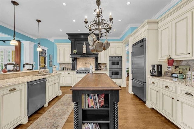 kitchen featuring pendant lighting, sink, appliances with stainless steel finishes, tasteful backsplash, and cream cabinetry