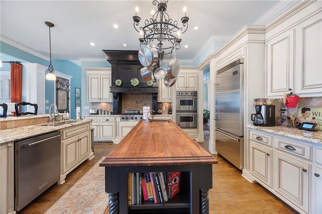 kitchen featuring cream cabinetry, appliances with stainless steel finishes, wood counters, and a sink