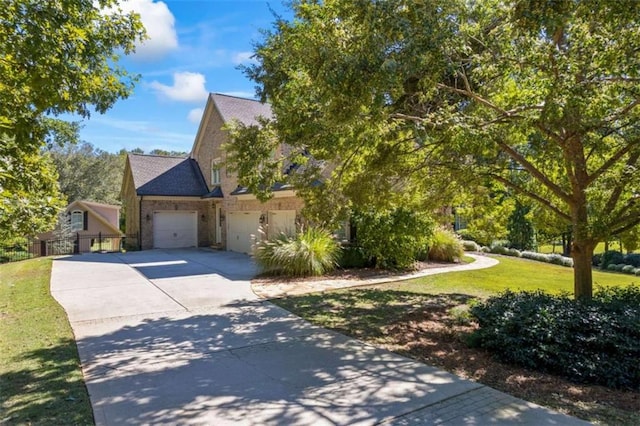 view of front of home featuring a front lawn, stone siding, fence, concrete driveway, and an attached garage