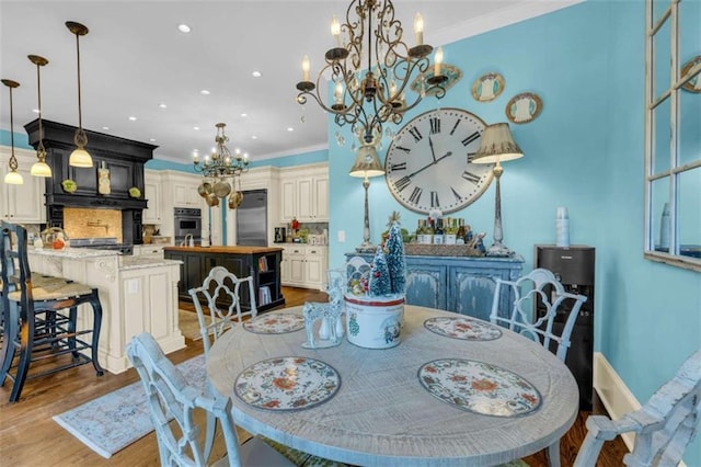 dining space with crown molding, a chandelier, and light wood-type flooring