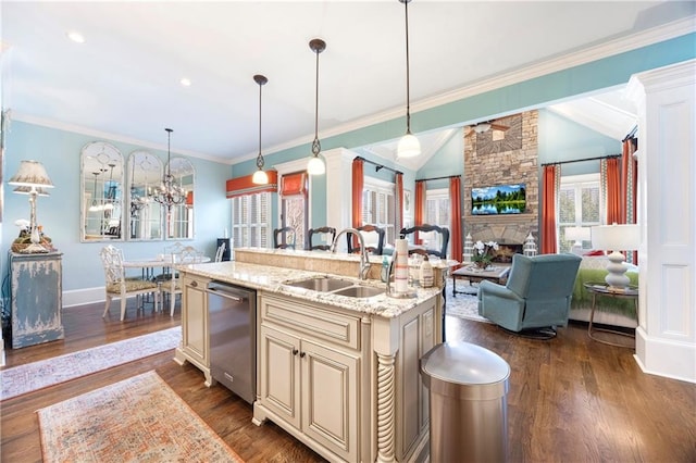 kitchen with cream cabinetry, a sink, stainless steel dishwasher, a fireplace, and lofted ceiling