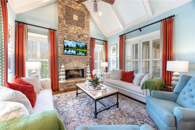 living area featuring beam ceiling, a fireplace, wood finished floors, high vaulted ceiling, and a ceiling fan