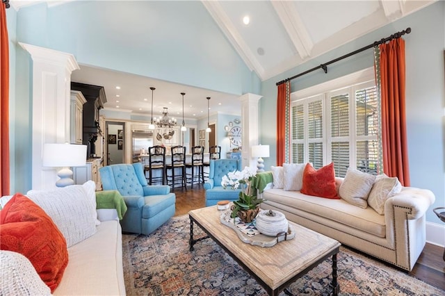 living area featuring wood finished floors, ornate columns, high vaulted ceiling, beam ceiling, and a chandelier