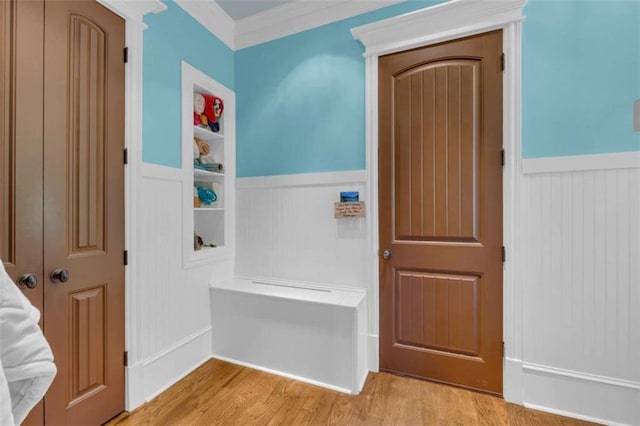 interior space with light wood finished floors, wainscoting, and crown molding