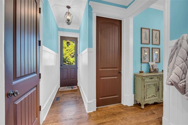 interior space featuring a notable chandelier, wood finished floors, wainscoting, and crown molding