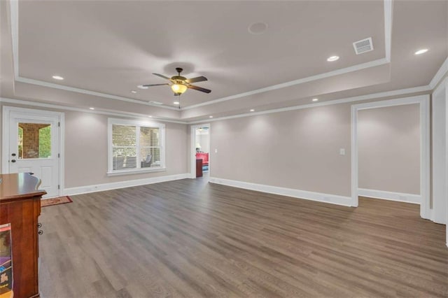 unfurnished living room with wood-type flooring, a tray ceiling, ceiling fan, and crown molding