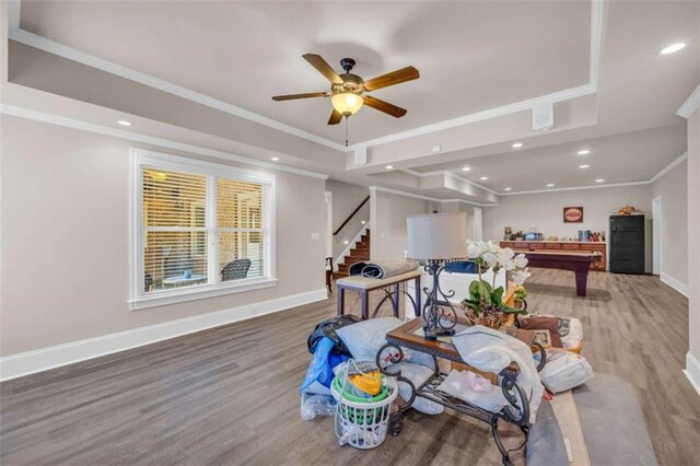 recreation room with baseboards, a raised ceiling, and crown molding