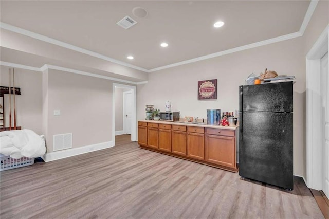 kitchen featuring light wood finished floors, visible vents, crown molding, light countertops, and freestanding refrigerator