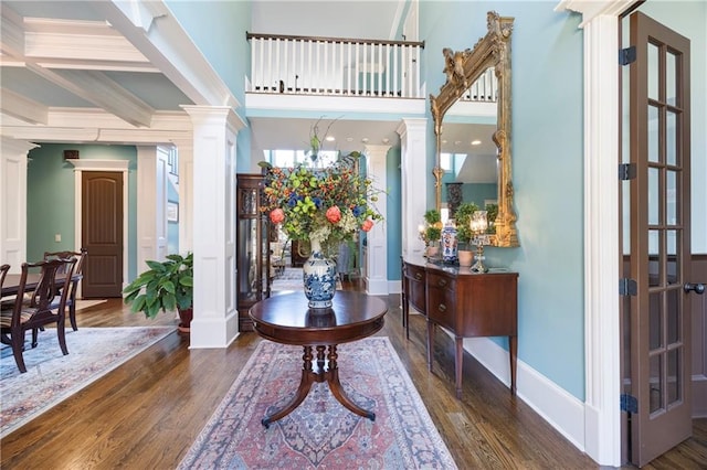 entrance foyer with wood finished floors, baseboards, and decorative columns