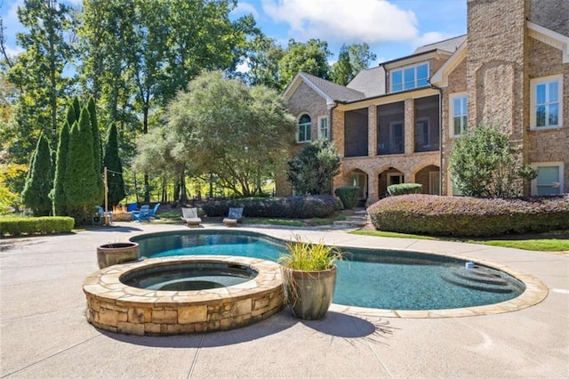 view of pool with a sunroom and an in ground hot tub