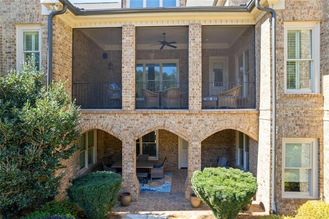 rear view of house with brick siding, a patio, and a sunroom