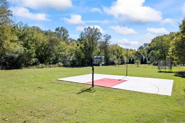 view of sport court featuring a lawn, community basketball court, and a trampoline