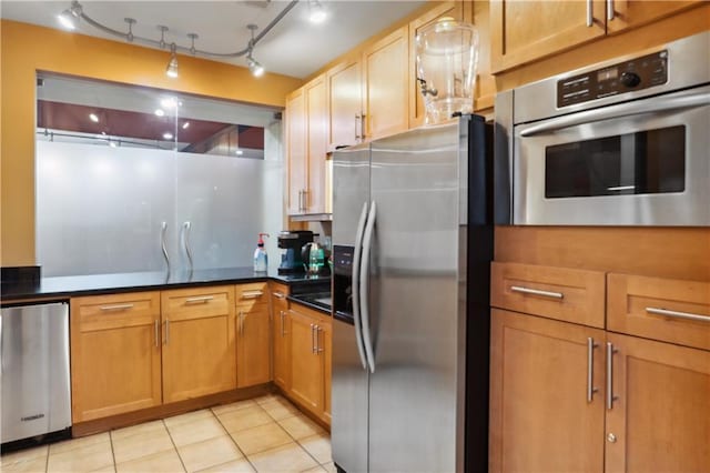 kitchen with track lighting, appliances with stainless steel finishes, and light tile patterned floors