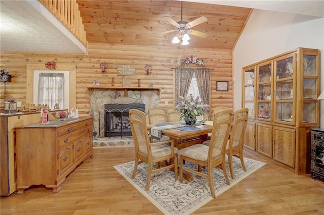 dining room with a fireplace, light hardwood / wood-style flooring, and high vaulted ceiling