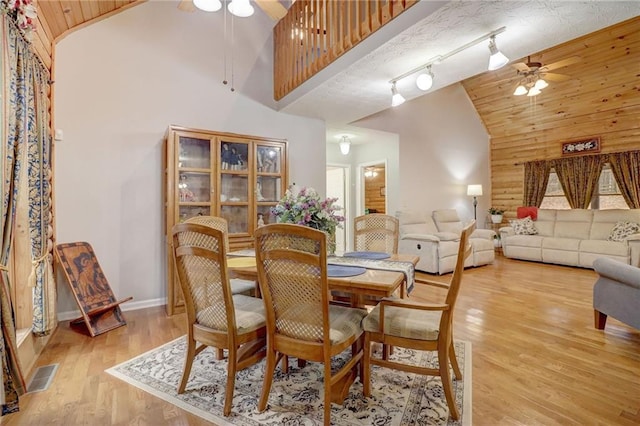 dining space featuring high vaulted ceiling, rail lighting, ceiling fan, and light wood-type flooring