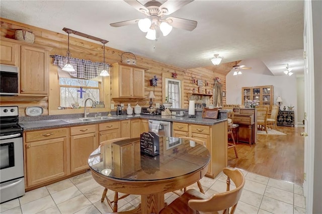 kitchen featuring light brown cabinetry, rustic walls, sink, light tile patterned floors, and appliances with stainless steel finishes