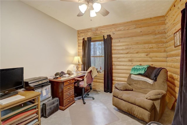 carpeted home office featuring ceiling fan and rustic walls