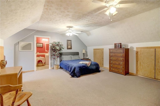 carpeted bedroom featuring ceiling fan, connected bathroom, vaulted ceiling, and a textured ceiling