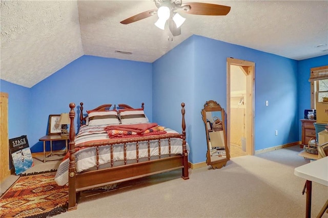 bedroom featuring ceiling fan, ensuite bath, vaulted ceiling, and a textured ceiling