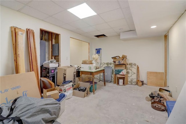 basement featuring a paneled ceiling and electric panel