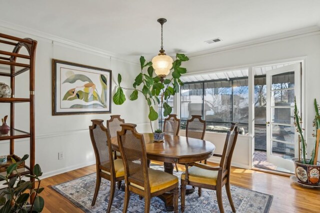 dining room featuring ornamental molding, visible vents, and wood finished floors