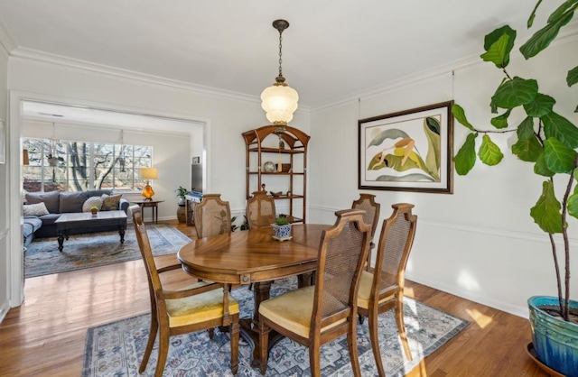 dining room with baseboards, ornamental molding, and wood finished floors