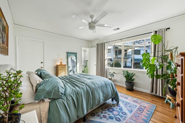 bedroom featuring visible vents, ceiling fan, baseboards, and wood finished floors