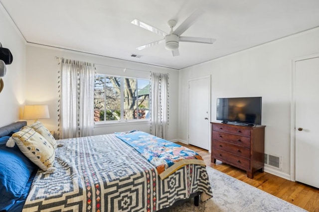 bedroom with a ceiling fan, baseboards, visible vents, and wood finished floors