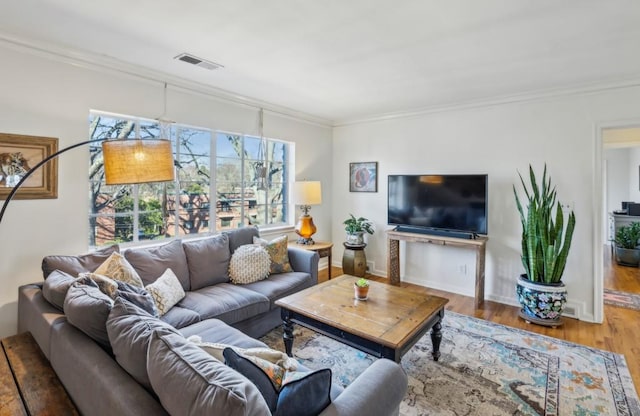 living room featuring visible vents, wood finished floors, and ornamental molding