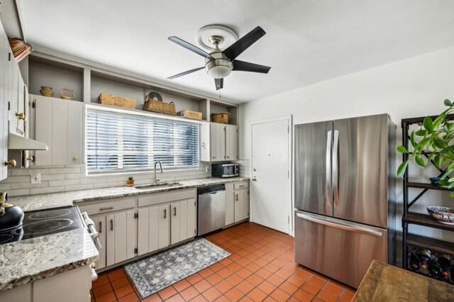 kitchen with light stone counters, stainless steel appliances, a sink, white cabinetry, and open shelves