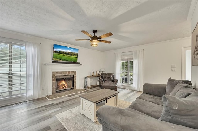 5407 Palmetto Ct, Flowery Branch, GA 30542 - living room featuring a textured ceiling, a ceiling fan, a fireplace, light wood-style floors, and ornamental molding