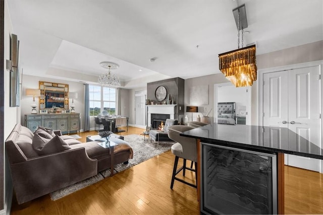 2881 Peachtree Rd NE Unit 1102, Atlanta, GA 30305 - living area featuring a chandelier, wine cooler, wood-type flooring, a lit fireplace, and a tray ceiling