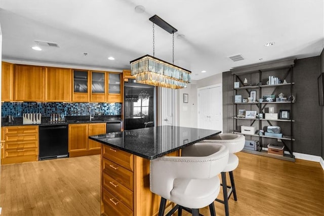 2881 Peachtree Rd NE Unit 1102, Atlanta, GA 30305 - kitchen featuring dishwasher, brown cabinets, light wood-type flooring, a kitchen bar, and a kitchen island