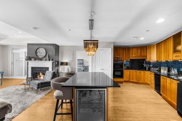 2881 Peachtree Rd NE Unit 1102, Atlanta, GA 30305 - kitchen featuring beverage cooler, black appliances, light wood finished floors, backsplash, and a breakfast bar