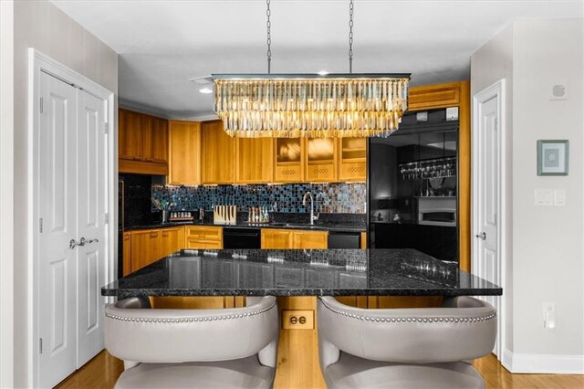 2881 Peachtree Rd NE Unit 1102, Atlanta, GA 30305 - kitchen with brown cabinets, backsplash, a sink, glass insert cabinets, and baseboards