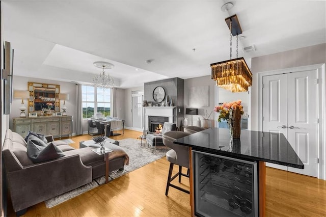 2881 Peachtree Rd NE Unit 1102, Atlanta, GA 30305 - living room featuring a chandelier, beverage cooler, light wood-type flooring, and a warm lit fireplace