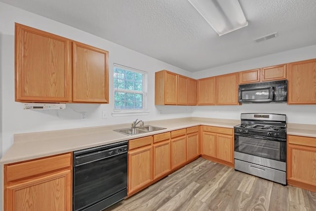 7459 Old Chapel, South Fulton, GA 30349 - kitchen with black appliances, a sink, a textured ceiling, light wood-style flooring, and light brown cabinets