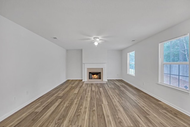 7459 Old Chapel, South Fulton, GA 30349 - unfurnished living room featuring a ceiling fan, wood finished floors, baseboards, and a warm lit fireplace