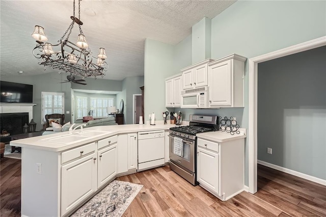 kitchen with white appliances, a peninsula, lofted ceiling, a sink, and open floor plan