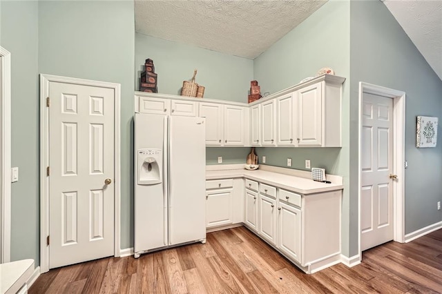 kitchen featuring white cabinetry, white refrigerator with ice dispenser, light wood-style flooring, and light countertops