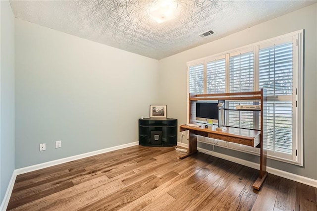 office area with visible vents, a textured ceiling, baseboards, and wood-type flooring