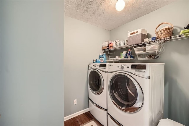 washroom with washer and dryer, a textured ceiling, wood finished floors, baseboards, and laundry area