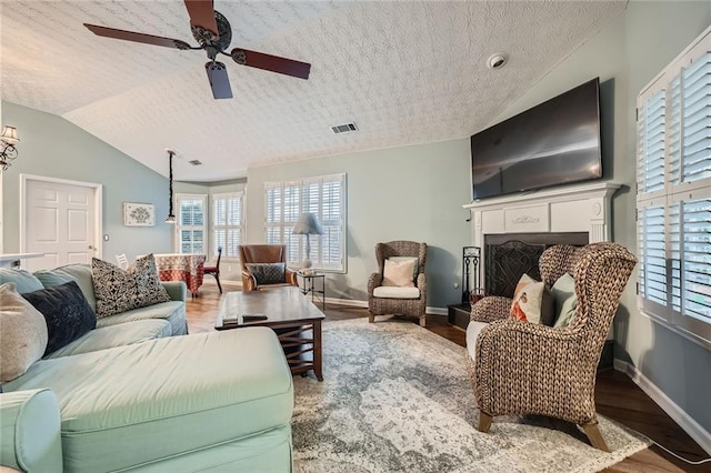 living area featuring vaulted ceiling, wood finished floors, visible vents, and ceiling fan