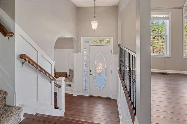 entryway featuring hardwood / wood-style floors, stairway, visible vents, and a towering ceiling