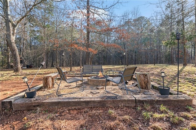 view of yard with a fire pit and a wooded view